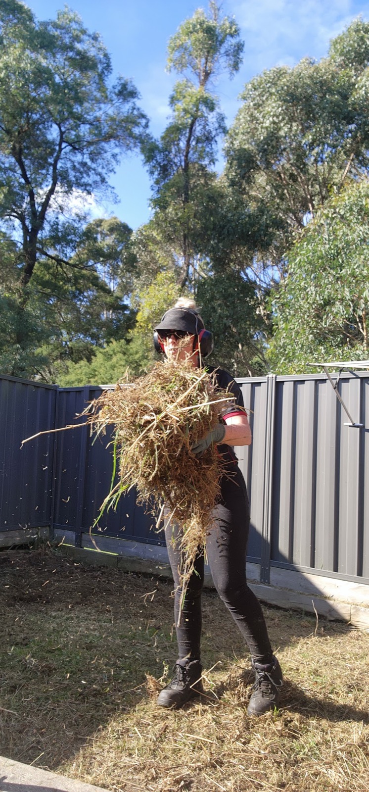 An armful of weeds pulled out of a garden bed by hand